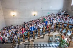 Grupa uczniów na schodach w budynku, wszyscy uśmiechnięci i pozujący do zdjęcia.