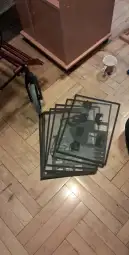 Kilka przezroczystych arkuszy z grafiką leży na podłodze obok rowerka dziecięcego.