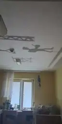 Cień postaci na suficie w jasnym pomieszczeniu.