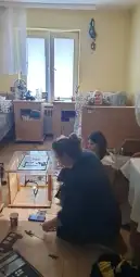 Kobiety pracujące nad projektem w pokoju, w tle mężczyzna relaksujący na kanapie.