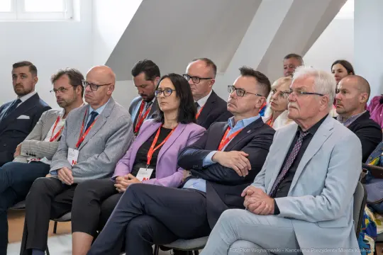 Grupa osób siedzących na konferencji, skupionych na prelekcji.