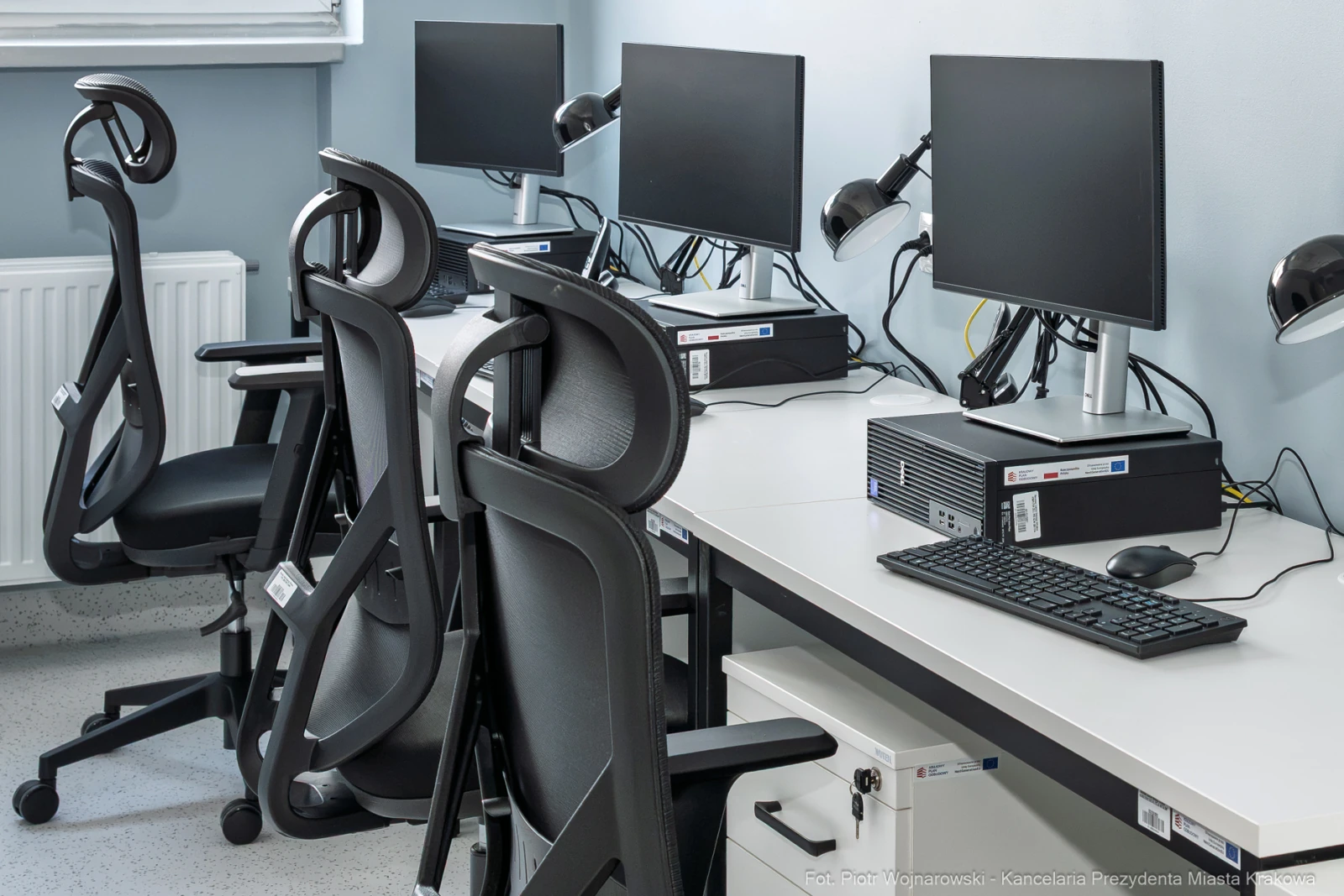 Puste stanowiska komputerowe z monitorami i ergonomicznymi krzesłami.  Autor: Piotr Wojnarowski