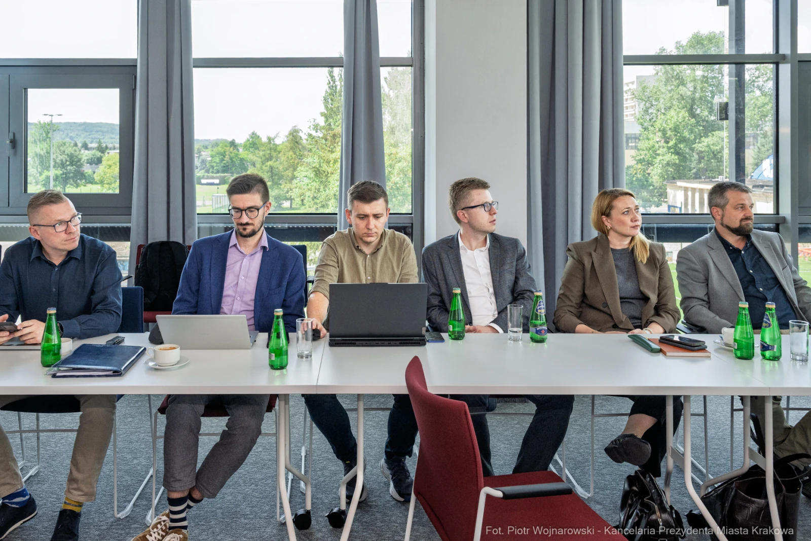 Grupa osób siedzących przy stole w sali konferencyjnej, z laptopami i butelkami wody.  Autor: Piotr Wojnarowski