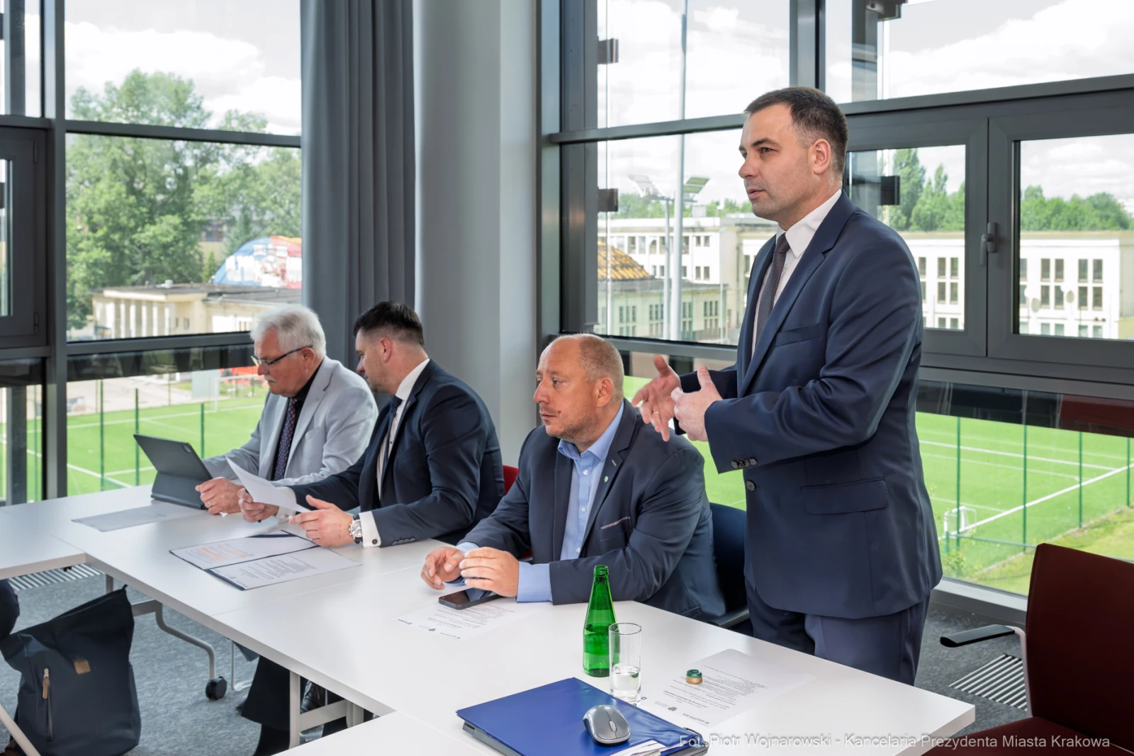 Czterech mężczyzn w garniturach podczas spotkania w biurze, jeden z nich przemawia.  Autor: Piotr Wojnarowski