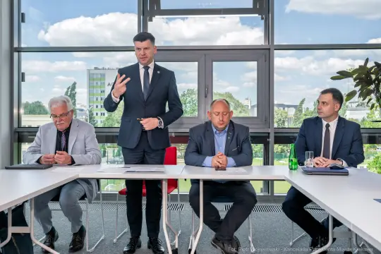 Czterech mężczyzn w garniturach podczas spotkania w biurze.