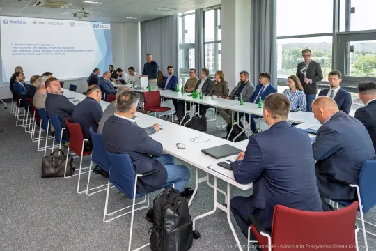 Spotkanie biznesowe w sali konferencyjnej z uczestnikami przy stole.