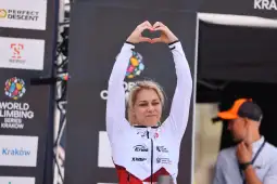 Sportowiec wykonujący gest serca podczas zawodów wspinaczkowych.