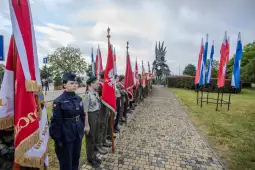 Młodzież z flagami narodowymi podczas ceremonii przy pomniku.