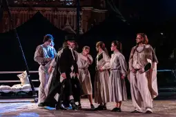 Grupa aktorów w kostiumach historycznych podczas przedstawienia teatralnego na świeżym powietrzu.