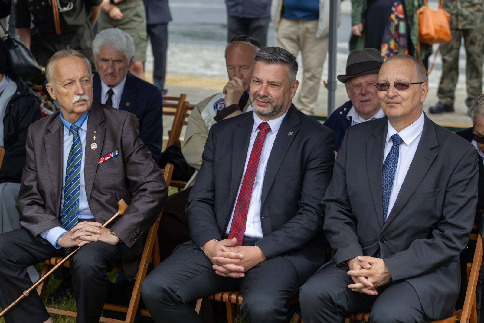 Trzech mężczyzn w garniturach siedzących na krzesłach podczas uroczystości.  Autor: Bogusław Świerzowski