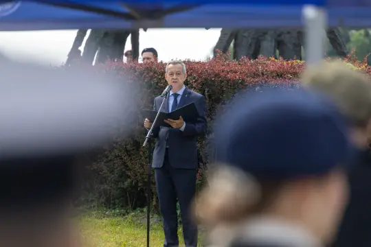Mężczyzna w garniturze przemawia do zgromadzonej publiczności.