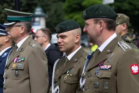 Trzej żołnierze w mundurach wojskowych podczas ceremonii.