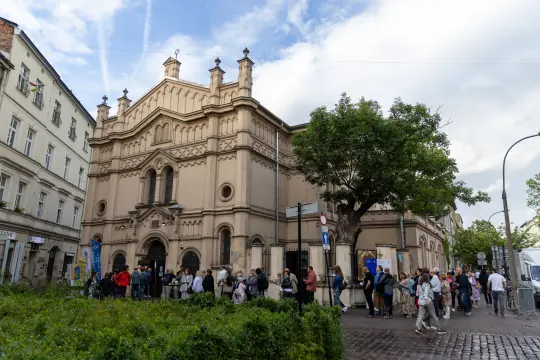 Budynek z architekturą neogotycką, przed nim kolejka ludzi.