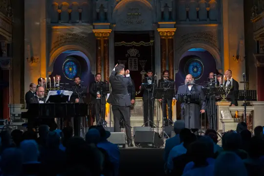 Koncert w synagodze z chórem i orkiestrą, widownia w tle.