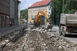 Maszyna budowlana pracująca na zniszczonym torowisku tramwajowym.