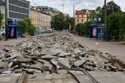 Zniszczona nawierzchnia tramwajowa z gruzem na ulicy.