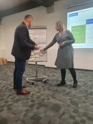 Osoby uczestniczące w warsztatach, omawiające zadania na tablicy z karteczkami.