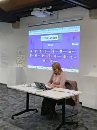 Kobieta siedząca przy stole z laptopem, na ekranie aplikacja Kahoot! z różnymi opcjami.