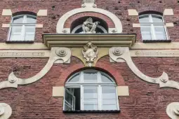 Fasada budynku z oknami i dekoracyjnymi detalami architektonicznymi.