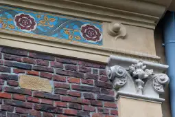 Detale architektoniczne z ozdobnym gzymsem i ceglaną ścianą.