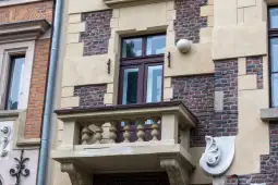 Balkon z balustradą na elewacji budynku z cegły i tynku.