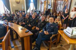 Grupa osób w mundurach siedząca w sali konferencyjnej.