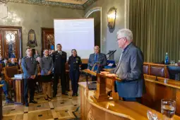 Uroczystość wręczenia nagród w sali obrad z uczestnikami w mundurach i mówcą przy mównicy.