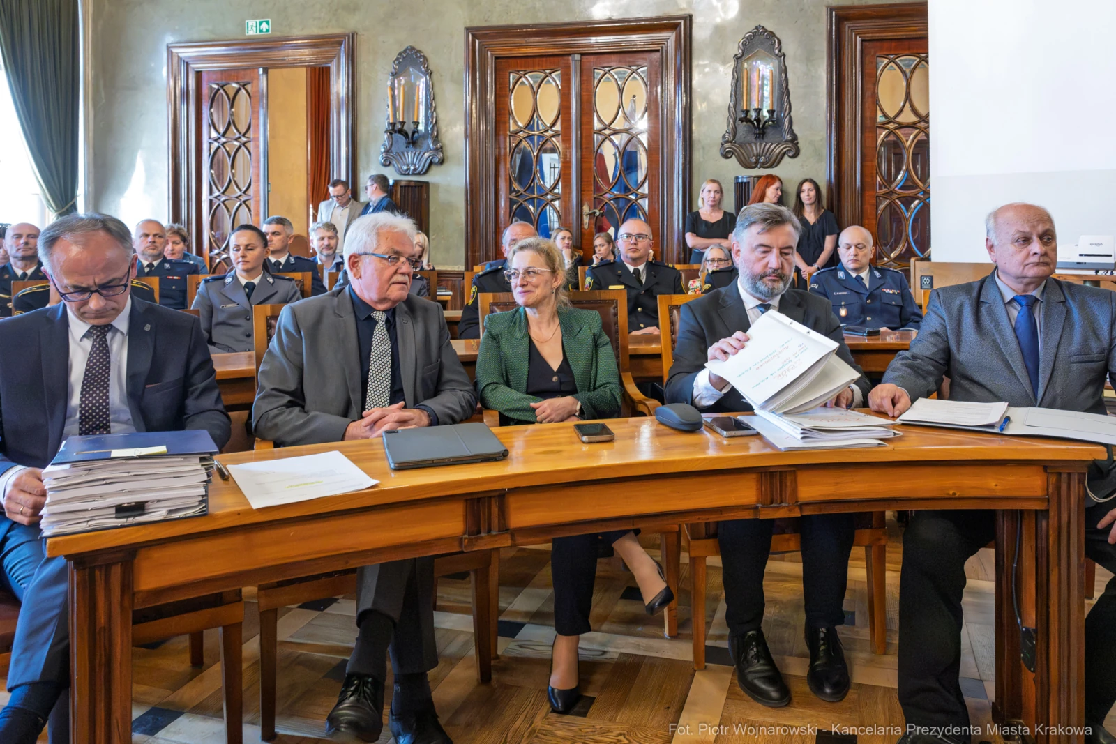 Spotkanie w sali obrad z uczestnikami w garniturach i mundurach, dokumenty na stole.  Autor: Piotr Wojnarowski