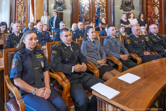 Uczestnicy ceremonii w sali obrad, w mundurach służbowych.