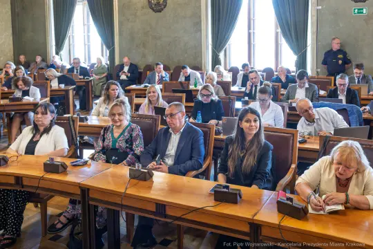 Zgromadzenie osób w sali obrad, skupionych na dyskusji.