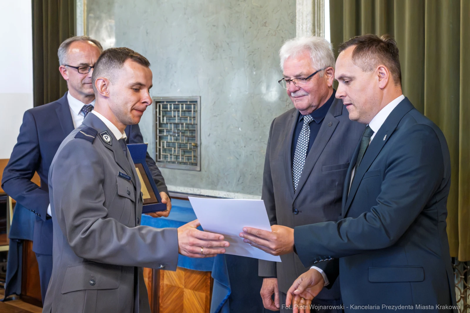 Wręczenie dyplomu przez urzędników, mężczyzna w mundurze odbiera dokument.  Autor: Piotr Wojnarowski