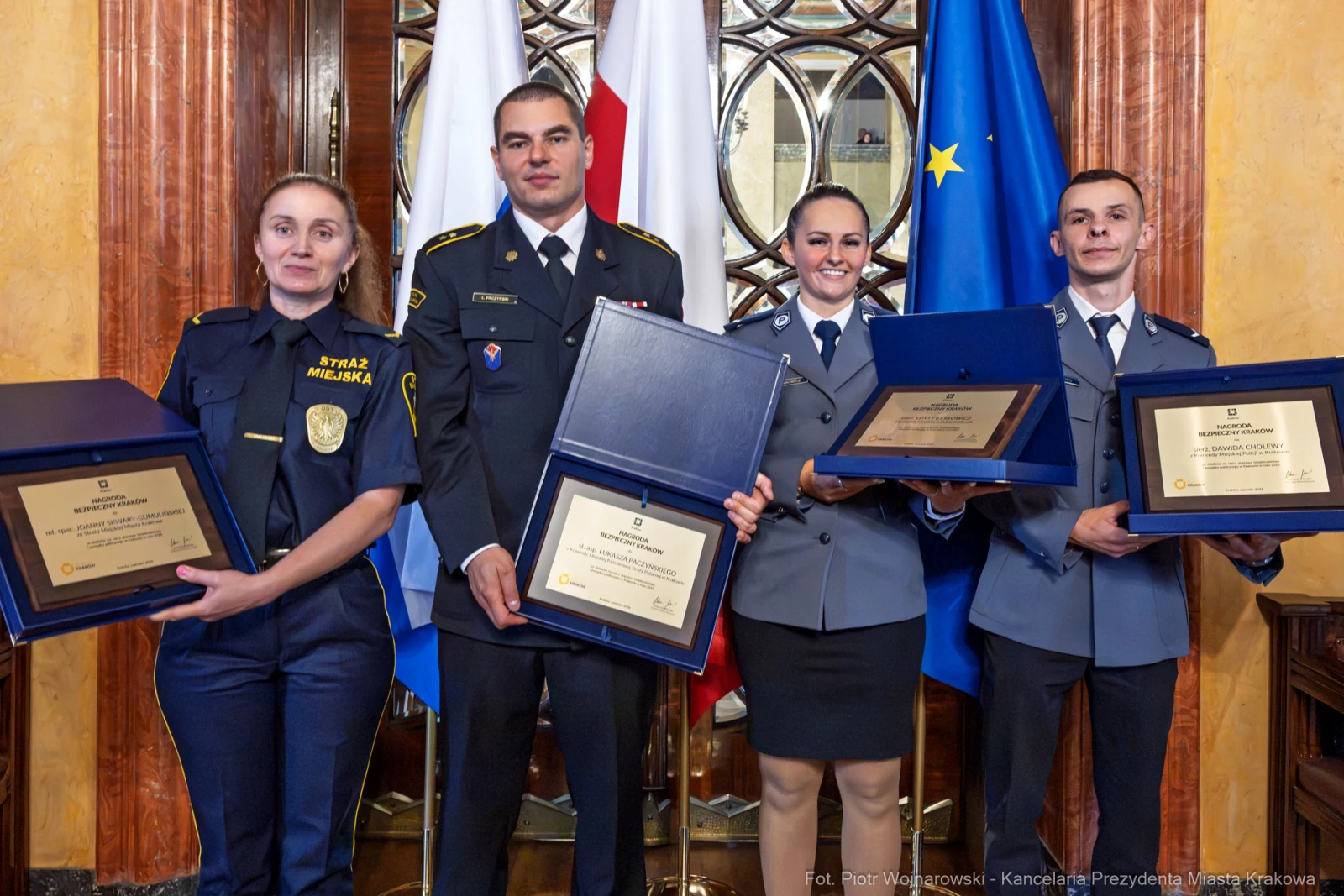 Cztery osoby w mundurach trzymają dyplomy i nagrody w eleganckim wnętrzu.  Autor: Piotr Wojnarowski