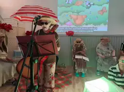 Osoby w kapeluszach i okularach przeciwsłonecznych uczestniczą w wydarzeniu artystycznym.