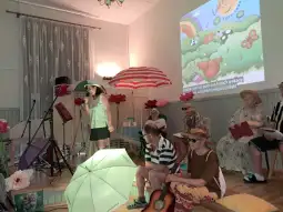 Kobieta śpiewająca na scenie, w tle kolorowe parasole i dekoracje letnie.