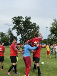 Radość zawodników po wygranej, jeden z graczy uniesiony na ramionach kolegów.