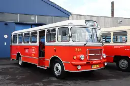 Czerwony autobus z numerem 216, stojący przed budynkiem.