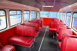 Pusty autobus z czerwonymi siedzeniami i dużymi oknami.