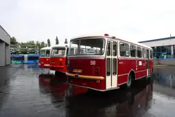 Dwa zabytkowe autobusy w kolorze czerwonym i kremowym na parkingu.