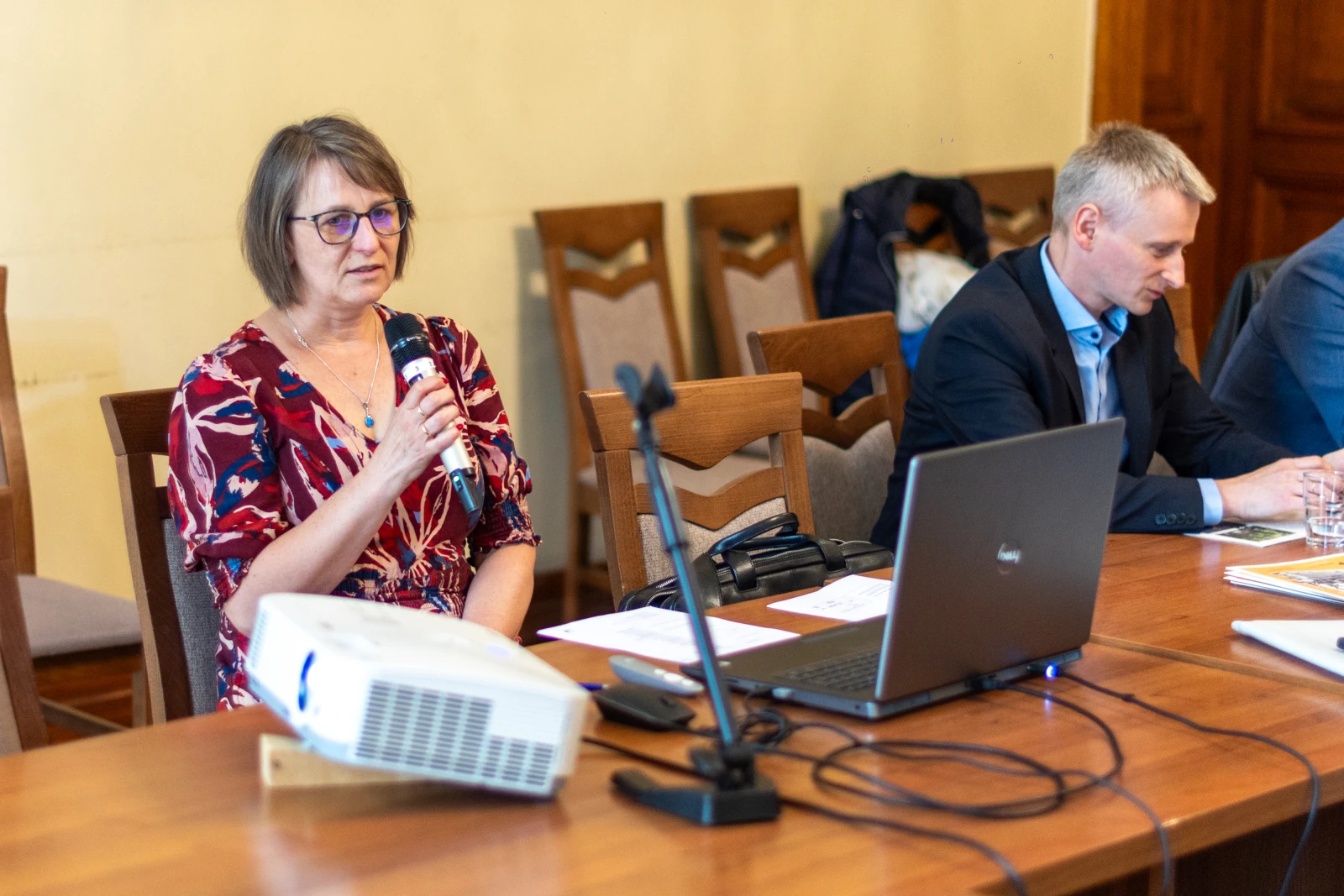 Kobieta z mikrofonem przemawia podczas spotkania, obok mężczyzna przy laptopie.  Autor: Bogusław Świerzowski