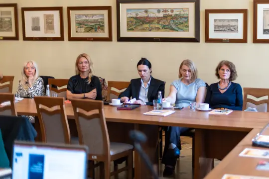 Grupa kobiet siedzących przy stole w sali konferencyjnej.
