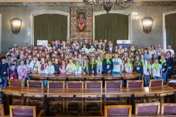 Grupa młodzieży z nauczycielami podczas wydarzenia w sali konferencyjnej.