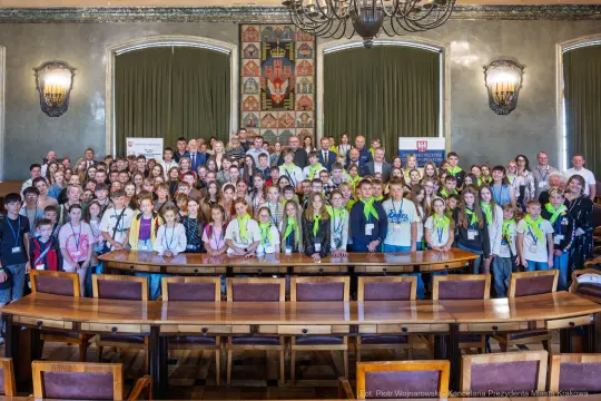Grupa młodzieży z nauczycielami podczas wydarzenia w sali konferencyjnej.