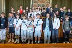 Grupa dzieci i młodzieży na tle sali, wszyscy w identyfikatorach.
