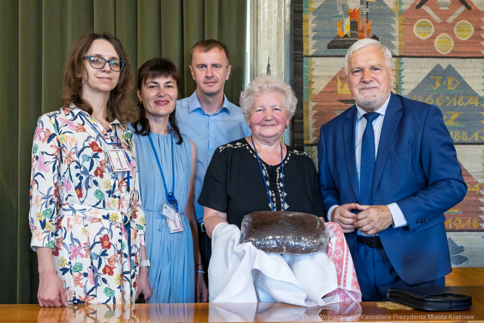 Grupa osób pozująca z tortem w ceremonialnym otoczeniu.  Autor: Piotr Wojnarowski