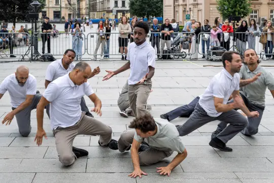 Grupa tancerzy wykonujących choreografię na ulicy, otoczona widownią.