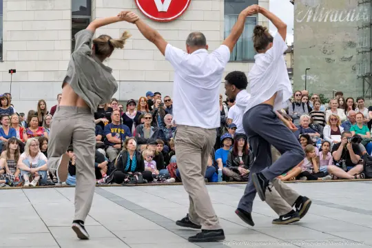 Grupa tancerzy wykonuje układ taneczny przed dużą publicznością.
