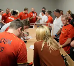 Grupa osób w czerwonych koszulkach, uczestniczących w wydarzeniu sportowym lub rywalizacji.