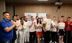 Grupa ludzi z pucharami, świętujących sukces na wydarzeniu sportowym.