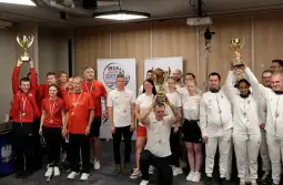 Zespół sportowy z pucharami i medalami, radość po zwycięstwie na zawodach.