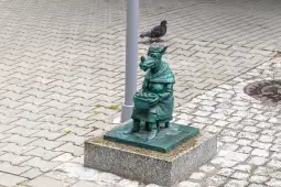 Figurka psa w kapeluszu siedzącego na ławce z koszykiem.